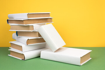 Books stacking. Open hardback books on wooden table and green background. Back to school. Copy space for ad text.