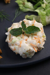 Creamy coleslaw salad garnished with mint leaves, served with crispy greens on a black plate, showcasing a fresh and colorful side dish perfect for healthy meals, restaurant menus, and fast food