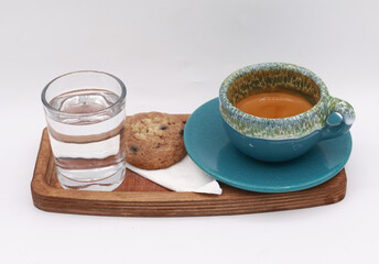 Minimalistic coffee serving scene with a cup of espresso, a glass of water, and a cookie on a wooden tray against a clean white background, capturing the essence of a cozy café moment and highlighting
