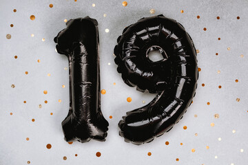 Black balloons shaped like the number 19 on a sparkling background