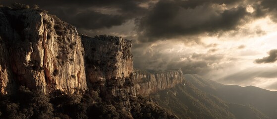 Majestic rocky cliffs under a dramatic cloudy sky at sunset with rays of light piercing through the clouds.