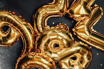 Golden balloons decorated for a festive celebration on a dark background