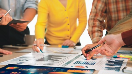 A diverse business team engaged in a collaborative session, analyzing market reports and financial charts on a modern office table, showcasing teamwork and productivity. SACTR