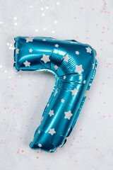 Bright blue balloon shaped like the number seven on a festive background