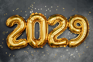Golden balloons display the year 2029 with sparkling stars on a dark background