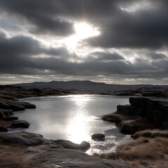 Obraz premium Serene Pond Reflecting Sunlight Piercing Through Overcast Sky in a Rocky Landscape.