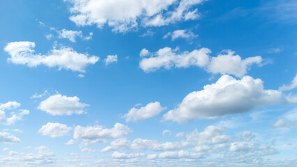 Vast blue sky with white fluffy clouds scattered across. The serene atmosphere evokes feelings of peace and tranquility, perfect for backgrounds or nature themes.