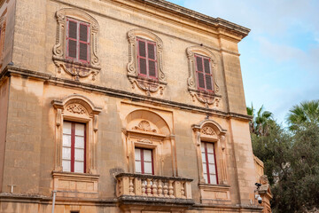Narrow streets of the old of Valletta on Malta with colourful balconies and red telephone boxes.Red traditional maltese balconies. Facade of old traditional building with red windows and balconies	

