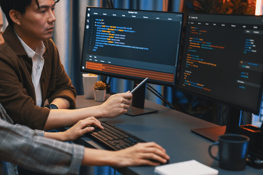 IT developers discussing with point to intelligent website development coder system running data online two screens information technology at neon light room at modern office. Infobahn.