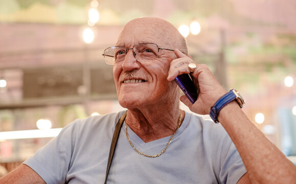 Close up portrait of senior  man sitting and smiling while using mobile phone. Elderly male using modern technology for online connection - Powered by Adobe