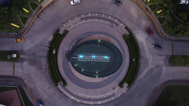 Overhead aerial view from a drone over a traffic circle in the Costa del Este neighborhood with the Panama City skyline over Panama City at sunset.