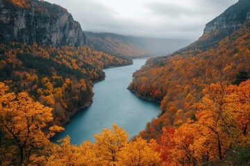 Vibrant autumn landscape with river winding through mountains in a serene valley filled with colorful foliage and misty sky