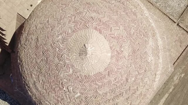 Top-down aerial view of a historic Persian dome structure built from traditional bricks in khorasan iran, sabzevar arg, captured from directly above in a dry landscape. The symmetrical architectural