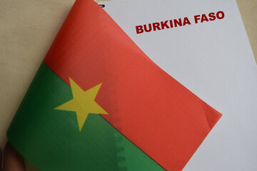 Concept of Burkina Faso write on book and the flag the Burkina Faso isolated on Wooden Table.