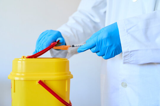 Doctor safely disposing hazardous  medical materials in bin over white background
