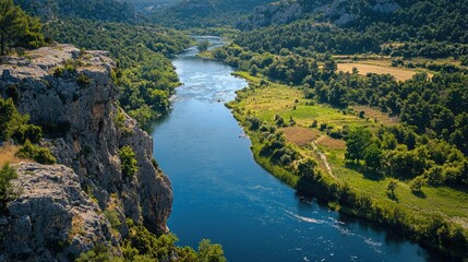 Scenic river valley with lush vegetation and towering cliffs.