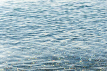 Crystal clear water gently flowing over pebbles on a sunny day