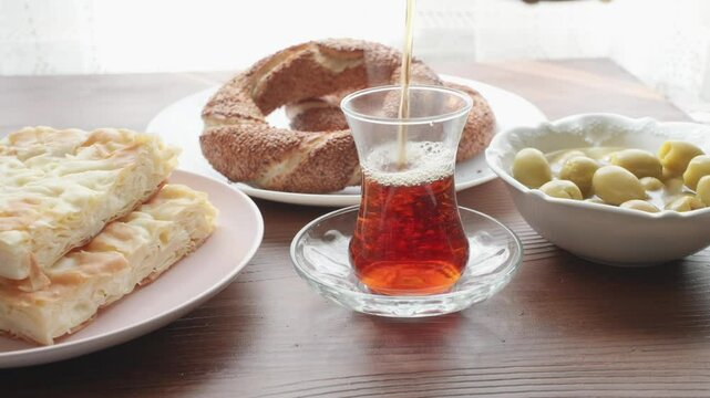 Local Turkish breakfast table Turkish tea, su boregi, green olives and simit bagel	