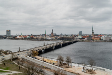 Riga big bridge for cars over large river that divides city coasts. City scape of riga buildings...