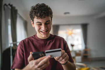 teenager young man sit at home use credit card shopping online