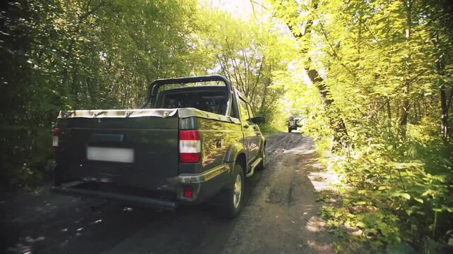 A pickup truck drives along a road in the forest.