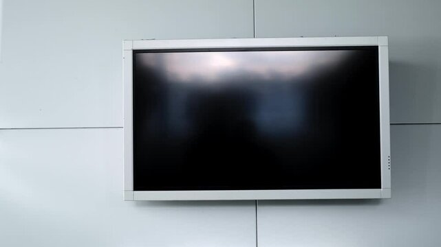 Modern flat screen lcd TV or oled, black screen blank HD monitor. Turned off display board on grey wall background in public place. Non-working television. Widescreen scoreboard. Advertising panel. 4K