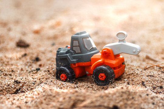 Spielzeugtraktor im sand von einem spielplatz mit sonnen von oben