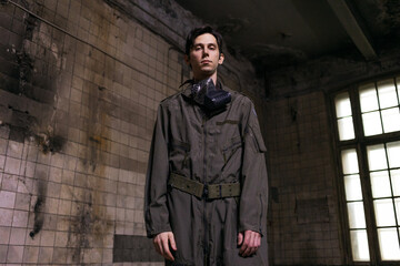 Naklejka premium Tactical operator in military jumpsuit wearing gas mask, gritty portrait in destroyed urban setting