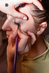 Makeup artist applying make up to a beautiful young pretty girl in a professional salon. Beauty,...