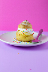 Cream puffs on a white plate sprinkled with colorful crumbs