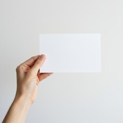 Fototapeta premium Hand holding blank white card in close-up for advertising mockup isolated on white background