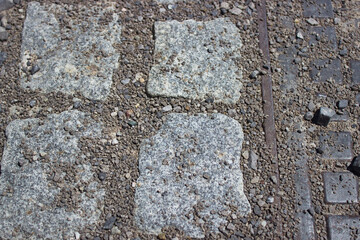 Granite cobblestones with gravel texture and iron line in pavement surface