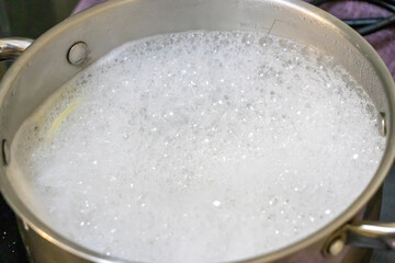 A pot filled with boiling water and bubbles, creating a dynamic kitchen scene. Ideal for culinary themes or cooking tutorials, showcasing the process of boiling ingredients.