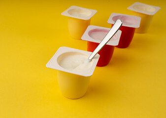 Yogurt cups set, pink and yellow fruit yoghurt in plastic pots, milk pudding container with spoon