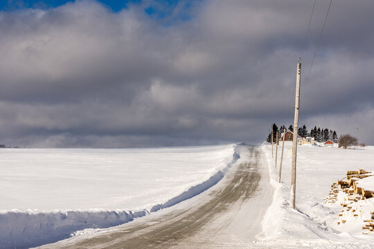 Country road with a power line running through snow-covered fields