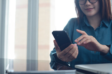 sian business woman using mobile phone, surfing the internet with laptop computer and digital tablet on office table. Woman using smartphone for online shopping, digital banking via mobile app