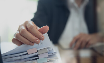 Document management. Businesswoman working with stack of paper files for searching and checking corporate files, document achieves on folders paper on office table, closeup