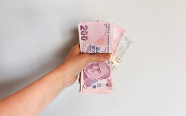 Hand holding a stack of Turkish Lira banknotes, representing finance, currency, and economic concepts