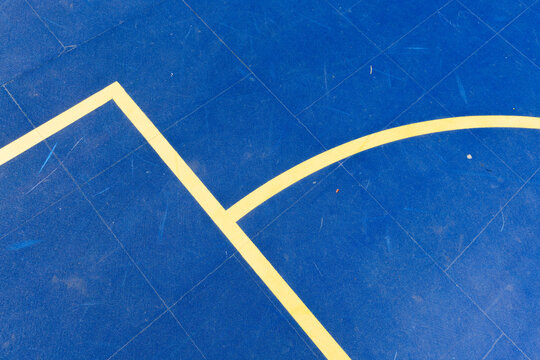 Geometric lines on a vibrant blue sports court surface, highlighting a basketball or futsal boundary with strong visual contrast. Stock photo
