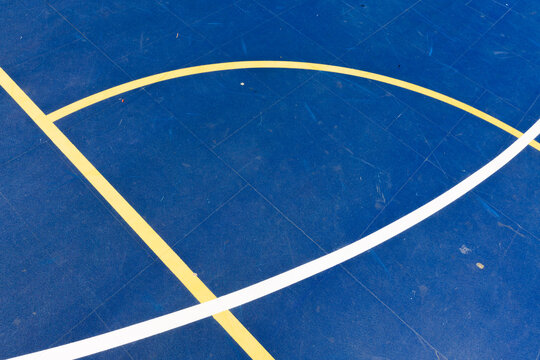 Detailed view of curved white and yellow boundary lines on a vibrant blue sports court, emphasizing geometry and motion. Stock photo