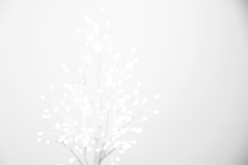Decorative tree with lights on light background, blurred view. Space for text