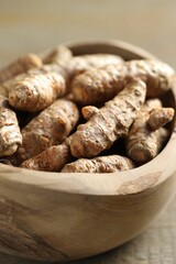 Raw turmeric roots in bowl on table, closeup