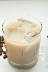 Coffee cream liqueur in glass and beans on white table, closeup
