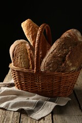 Different loaves of fresh bread in basket on wooden table