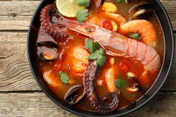 Delicious seafood soup in bowl on wooden table, top view