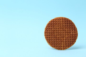 One tasty round waffle on light blue background. Space for text