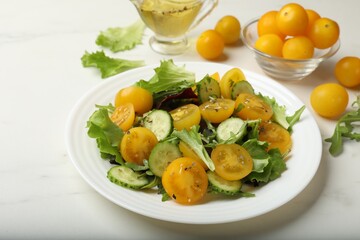 Fresh salad with yellow tomatoes on white table, closeup