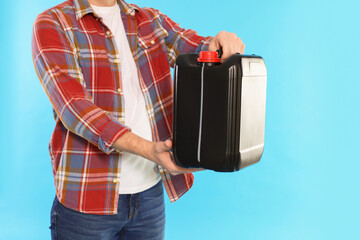 Man holding plastic canister on light blue background, closeup. Space for text