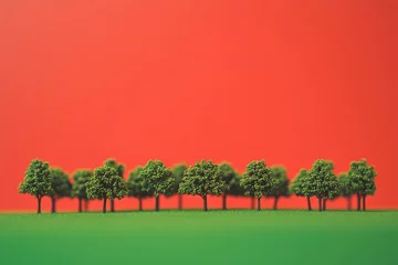Fototapete Miniature trees in a row against a vivid red background. © MrHamster