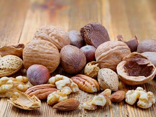 A close up photo of various raw nuts both shelled and unshelled on a wooden table.